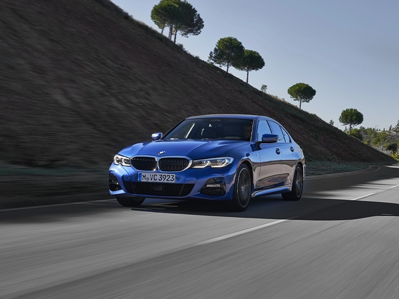 Blue BMW 330i driving on road