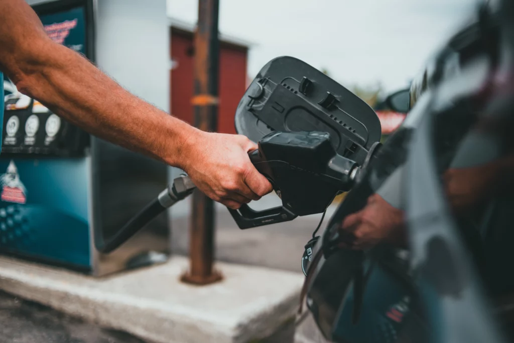 Hand holding gas pump and filling up a vehicle